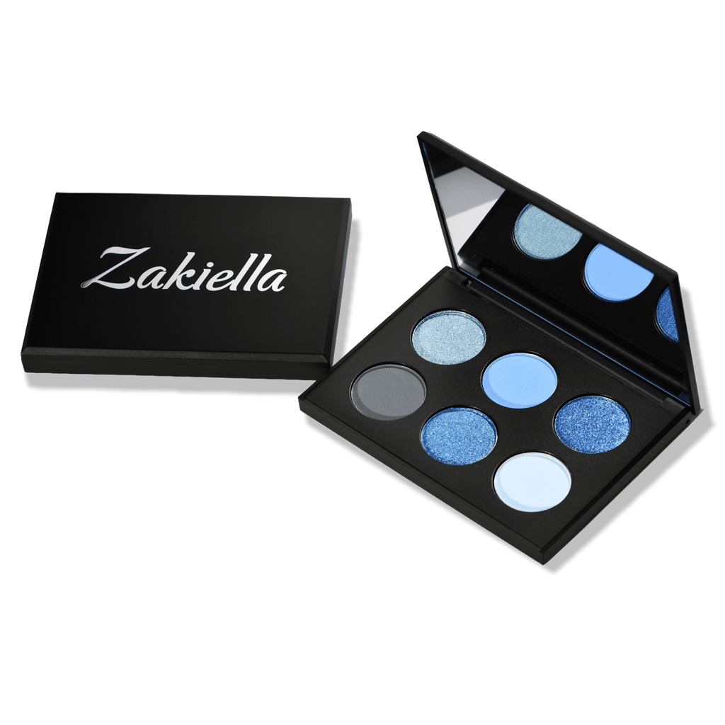 Ocean Eyeshadow Palette shown open with a closed one beside it showing the Zakiella logo. The eyeshadows are a mix of metallic and matte shades of blue and charcoal.